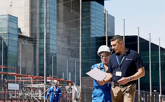 Two Equans employees looking at document on site
